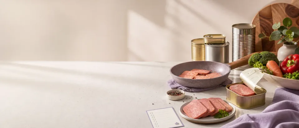 Warm kitchen still life with canned luncheon meat, sliced cooked canned meat, vegetables, and a pregnancy food-safety checklist.